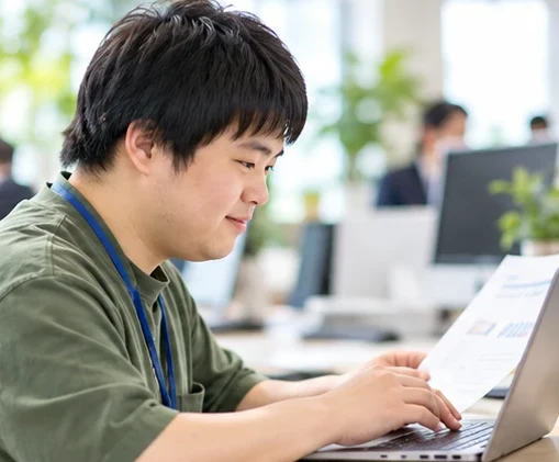 資料を見ながらPCで作業するメンバー